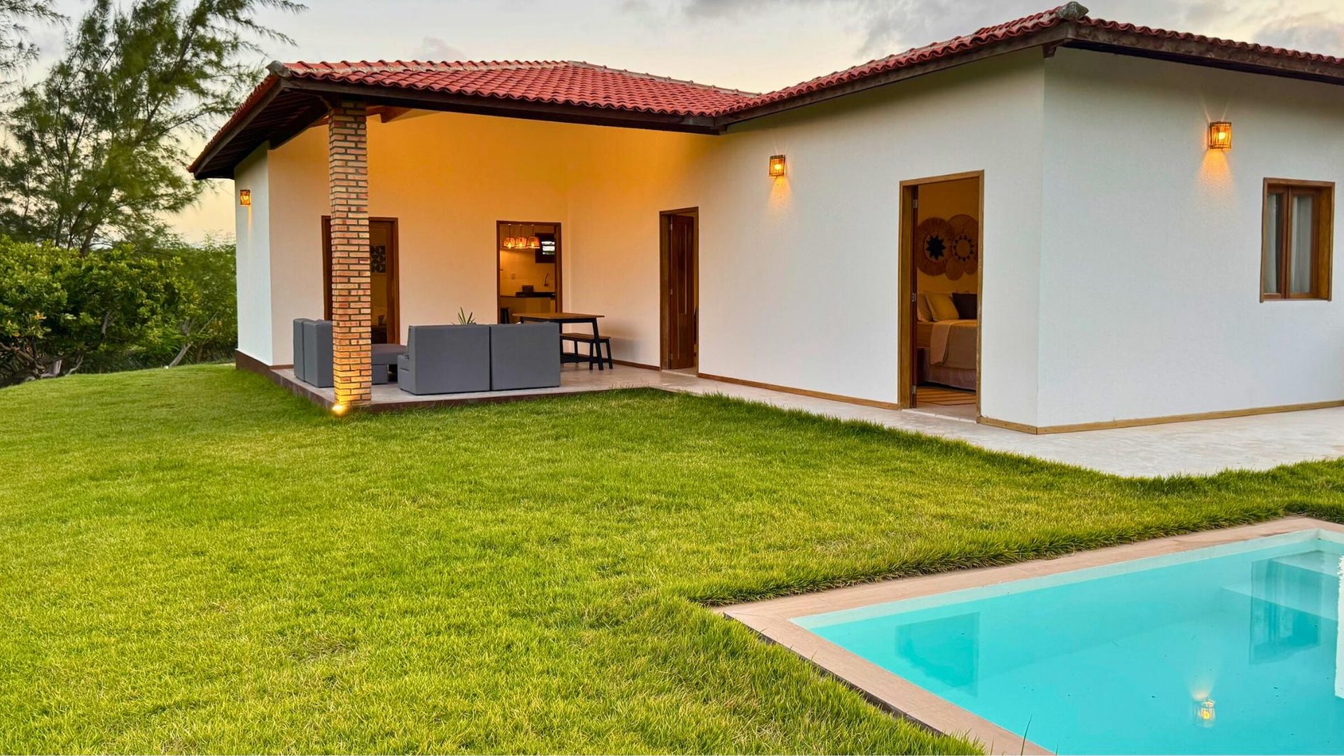 Coast House ao entardecer: casa iluminada com piscina e jardim na Praia do Retirinho