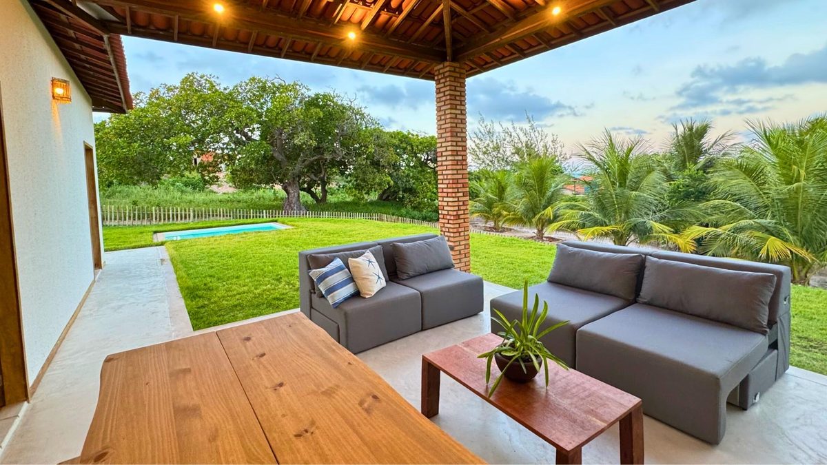 Varanda da Coast House com vista para o jardim, a piscina e os coqueiros